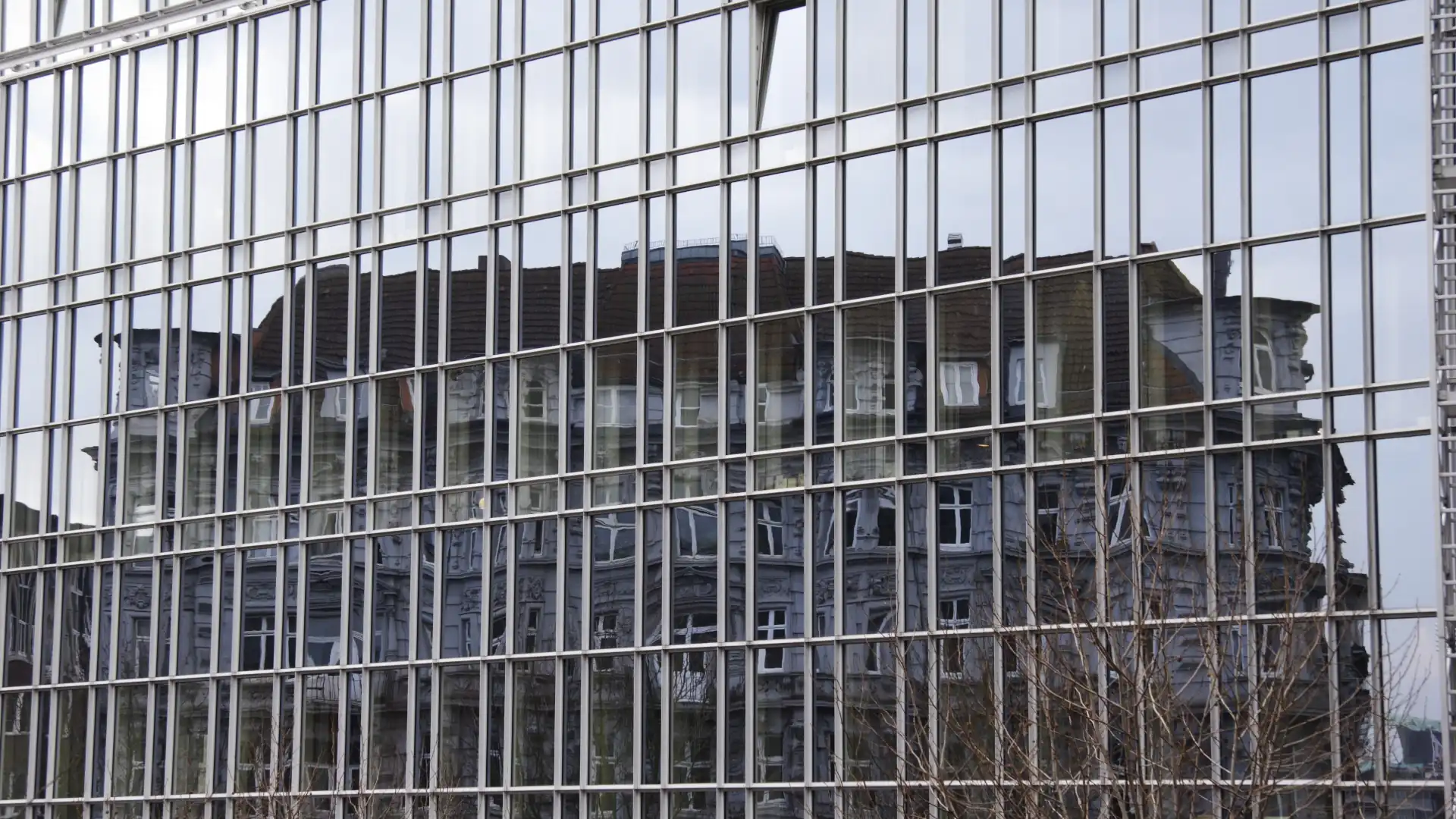 Are Glass Floors Safe – The outside of a large glass building, made of glass panels, with the reflection showing